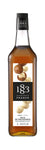1883 Macadamia Nut syrup is light brown in color with whole brown and shelled white macadamia nuts on the label