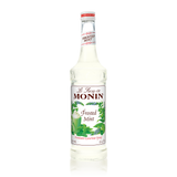 a clear syrup with green mint leaves and a green cup with whip cream on top giving you a chilly minty feel 