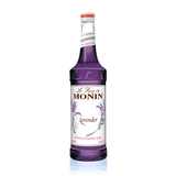 a glass bottle filled with bright purple lavender syrups a formal looking label with lavender plant branches on it and the work Lavender in the middle