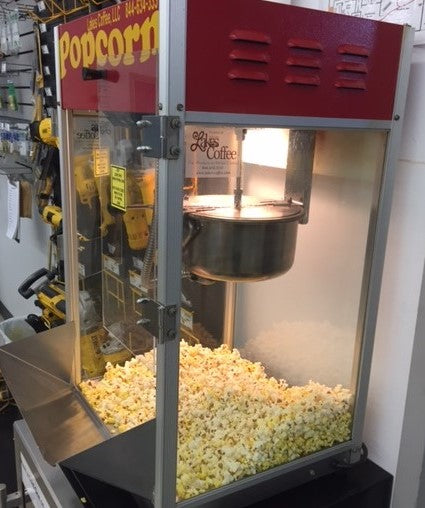 Gold Medal popcorn machine with buttery golden yellow popcorn at the bottom all nicely popped with stickers reading Lakes Coffee on the side of this popcorn machine 