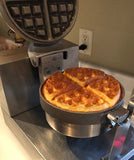a hot waffle maker with a huge golden brown Belgian waffle still in the waffle maker perfectly cooked