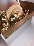 a box of coffee filled with gold foil packets and a packet of white coffee filters 