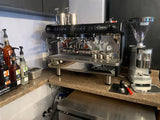 Coffee shop products including a new Cimbali espresso machine with a Mazzer Grinder and off to the side a few barista tools 