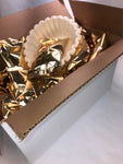 a white box with gold packets of coffee and a sleeve of coffee filters in the box