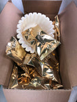 A box of highlander Grog gold colored coffee packets with a sleeve of coffee filters 