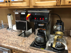 Bunn coffee brewer set up at an office with coffee pots and a grinder 