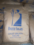 a 50# bag of light brown sugar from United Sugars  sitting on a pallet of brown sugar bags